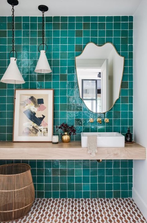 a bold bathroom with a turquoise tile wall, a floating vanity, pendant lamps and a quirky mirror is wow