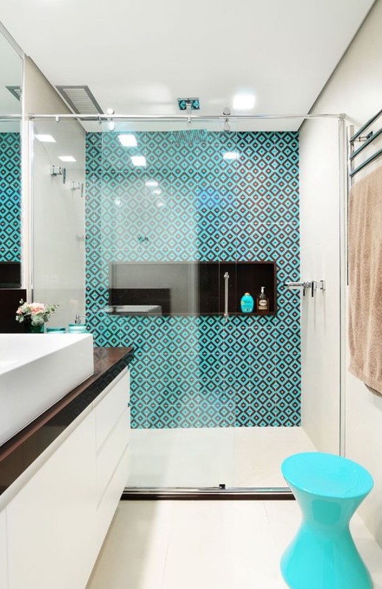 a bold modern bathroom in neutrals, with a dark tabletop, a turquoise and brown tiles and a turquoise stool