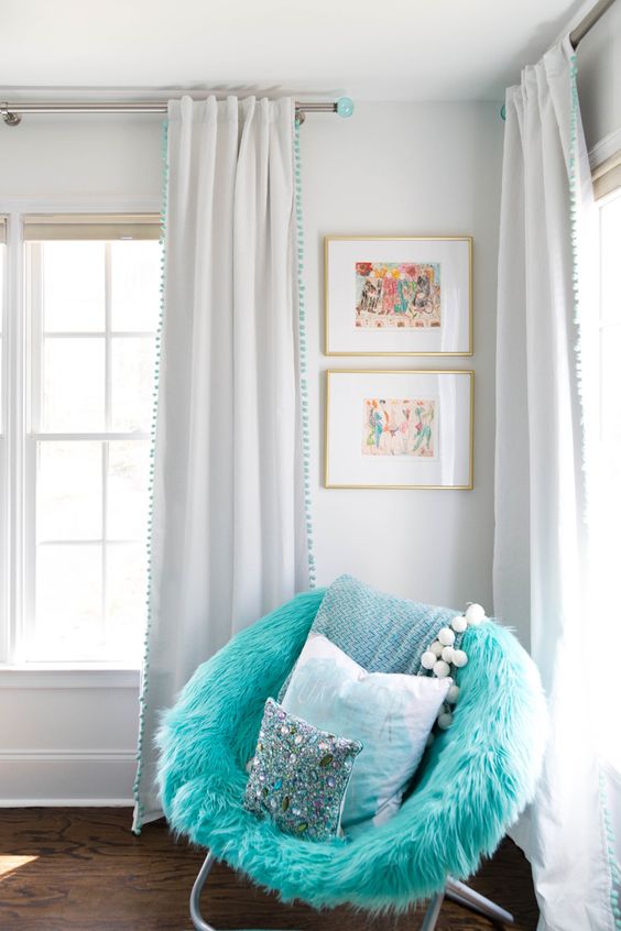 a bright turquoise chair with faux fur and pillows is a cool and lovely touch of color to the space