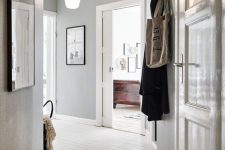a casual entryway with light grey walls, a whitewashed wooden floor and gorgeous artworks to make the space cooler