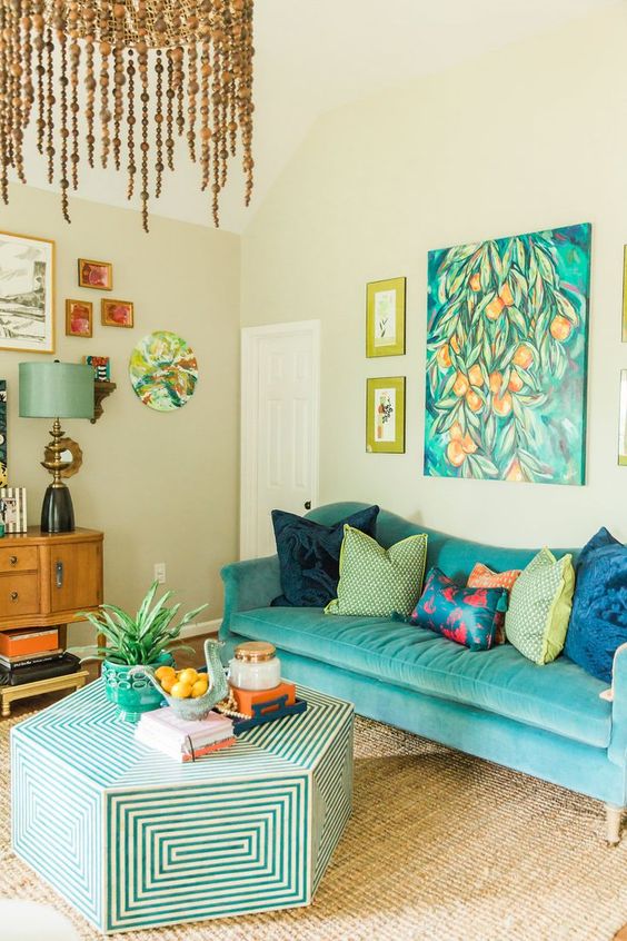 a colorful living room with a turquoise sofa and a catchy geometric coffee table, bold artwork and a beaded chandelier