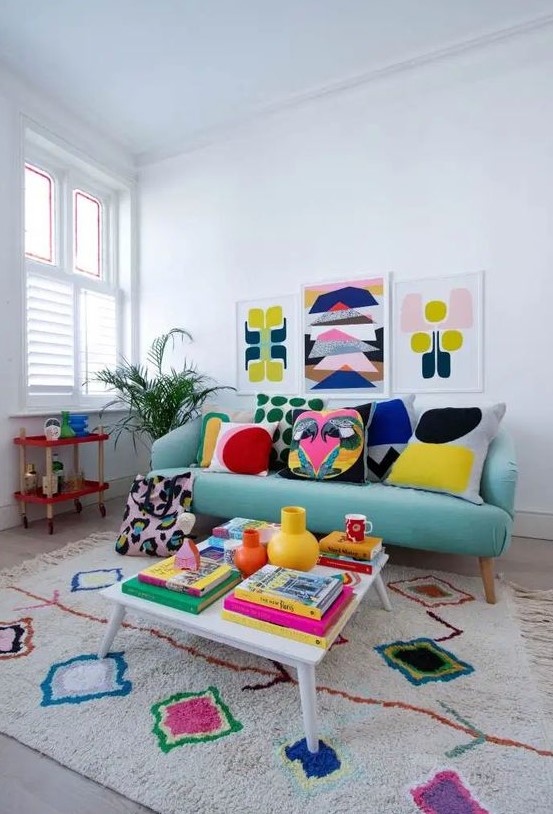 a colorful retro-inspired living room with a turquoise sofa, a colorful rug, a gallery wall, pillows and books fill the space with bright colors