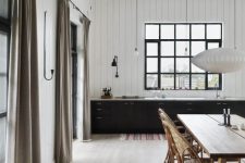 a contrasting kitchen with white walls, black cabinets, whitewashed floors and a lovely wooden dining set