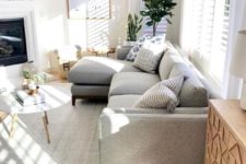 a cozy modern living room with a grey sofa, a built-in fireplace, a round table, potted plants and lots of natural light
