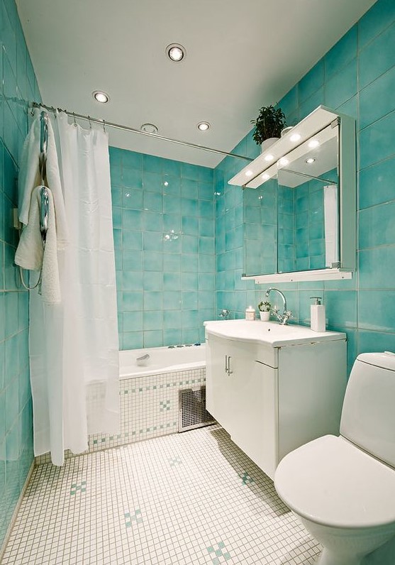 a dreamy bathroom with turquoise tiles, neutral ones, neutral furniture, white appliances built-in lights and a large mirror