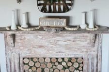 a faux shabby whitewashed wooden fireplace with wood slices in it and some rustic decor is chic