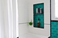 a graphic black and white bathroom with turquoise tile lining, with a niche and a black and white curtain