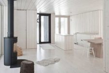 a minimalist space with whitewashed walls, a ceiling, a floor and wooden furniture and a hearth