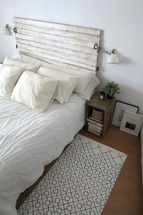 a neutral farmhouse bedroom with a bed with a whitewashed headboard, stained nightstands, neutral bedding and artwork, sconces