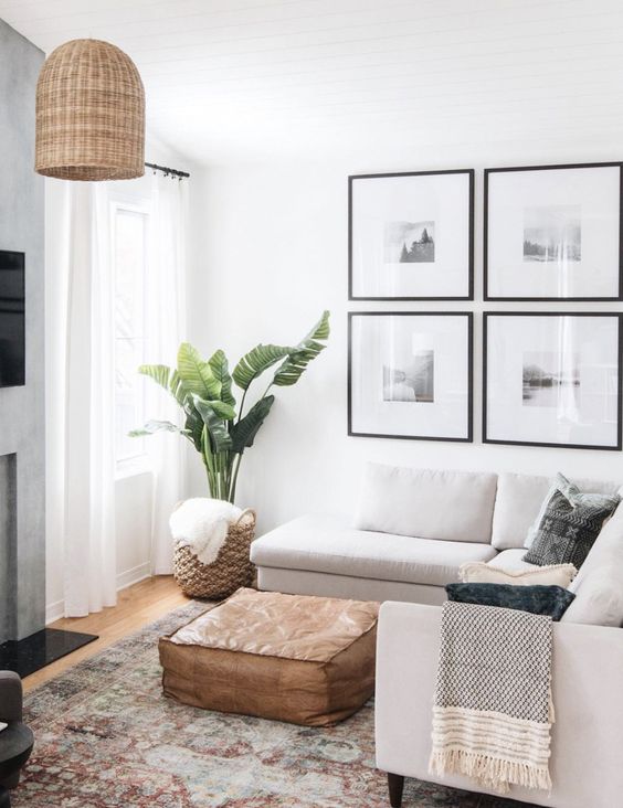 a neutral small living room with a sectional, a leather ottoman, a gallery wall, a woven lamp and a potted plant