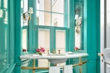 a refined vintage bathroom all painted in turquoise, with a free-standing sink and touches of gold looks very chic