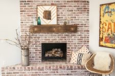 a rustic whitewashed red brick fireplace with a wooden mantel, mid-century modern decor and printed pillows