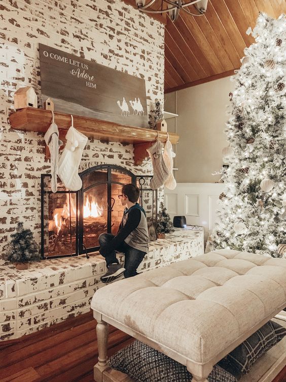 a shabby chic whitewashed brick fireplace with a metal screen, a wooden mantel and some neutral Christmas decor