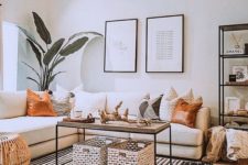 a small boho living room with a white sectional, woven and wooden items, a gallery wall, potted plants and printed pillows