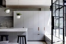 a stylish modern kitchen with a whitewashed concrete floor, grey cabinets, grey furniture and potted greenery