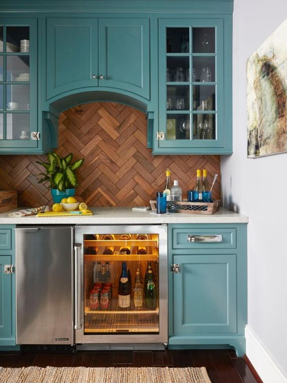 a turquoise home bar with shaker style cabinets, white stone countertops, a wooden chevron tile backsplash and a wine cooler