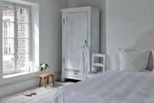 a vintage-inspired bedroom with white walls, a whitewashed floor and whitewashed furniture plus lots of natural light