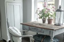 a vintage space with a white wardrobe and chair and a whitewashed and distressed table, a basket for storing blankets and pillows
