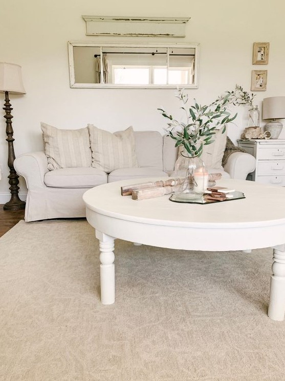 a white shabby chic living room with a creamy Ektorp sofa, a low round table, a nightstand, floor and table lamps