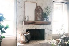 a whitewashed brick fireplace with a wooden mantel, rustic decor and potted greenery is rustic and cozy