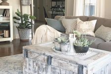 a whitewashed chest as a coffee table on casters and a tray with potted plants for finishing off a farmhouse living room