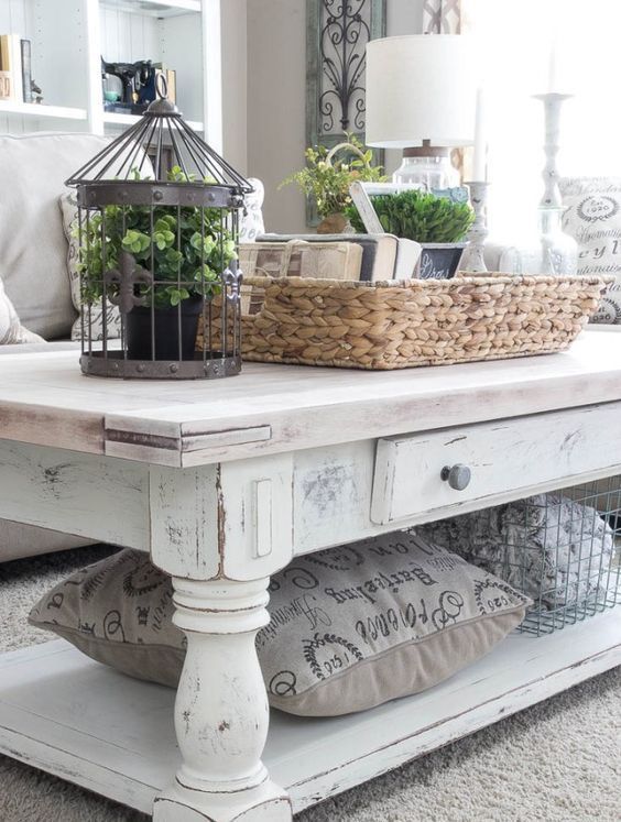 a whitewashed table used as a coffee one, with drawers and an additional open shelf is a functional and refined idea for a farmhouse space