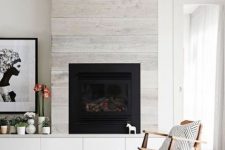 a whitewashed wood clad fireplace perfectly matches a contemporary space and the neutral color scheme applied here