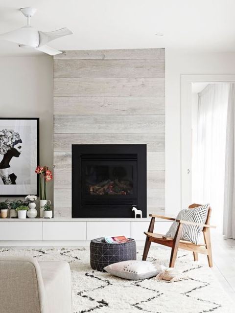 a whitewashed wood clad fireplace perfectly matches a contemporary space and the neutral color scheme applied here