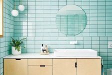 an airy modern bathroom with turquoise tiles, white on the floor, a floating plywood vanity and white appliances