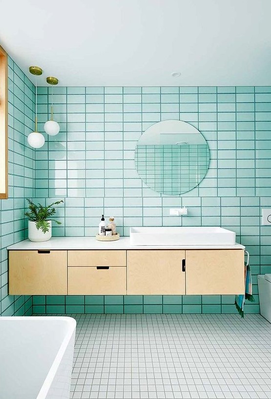 an airy modern bathroom with turquoise tiles, white on the floor, a floating plywood vanity and white appliances