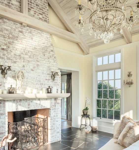 an elegant whitewashed brick fireplace with a refined metal screen, a white mantel with candles for a vintage farmhouse interior