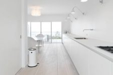 an ultra-minimalist white kitchen with a whitewashed wooden floor that softens the look of the space a bit