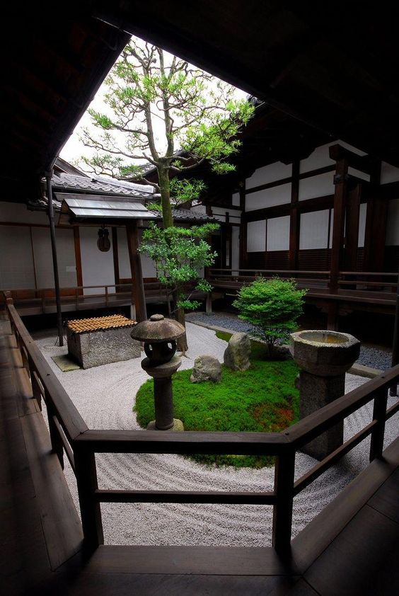 un patio japonés con césped, faroles de piedra y una tina de agua de piedra, árboles bajos se ve muy refrescante