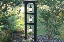 a Japanese front yard with pebbles, some thin trees and a stand with lanterns is a lovely idea to apply to your outdoor space