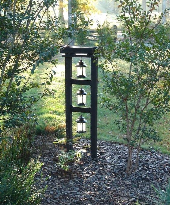 a Japanese front yard with pebbles, some thin trees and a stand with lanterns is a lovely idea to apply to your outdoor space