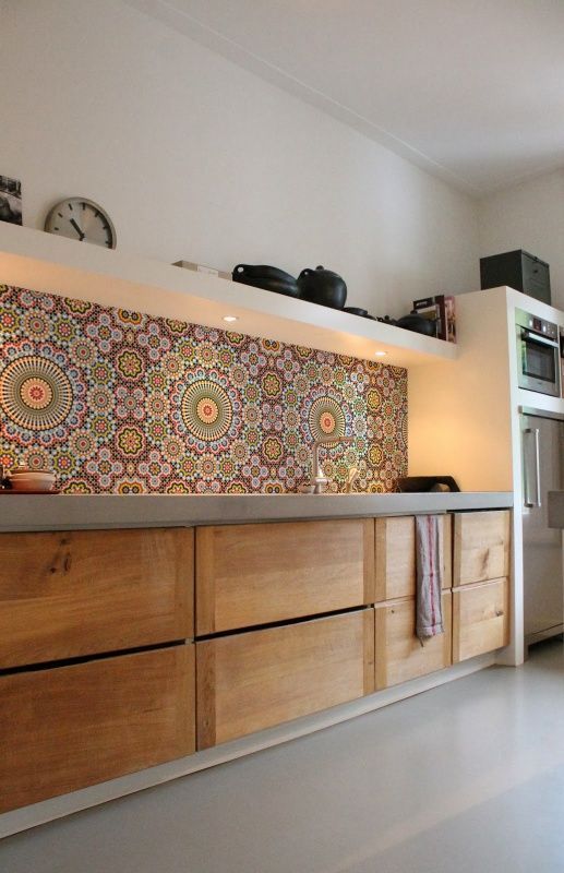 a bright kitchen with sleek wooden cabinets, concrete countertops and a colorful tile backsplash
