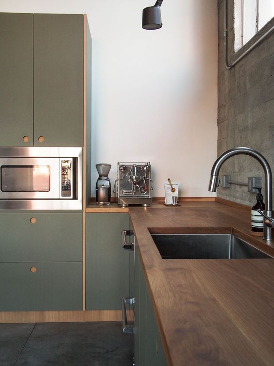 a chic minimalist green kitchen with dark stained wooden countertops and no handles is a bold and cool space with a moody feel