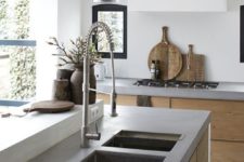 a chic minimalist kitchen with sleek wooden cabinets, concrete countertops, white walls and pendant lamps