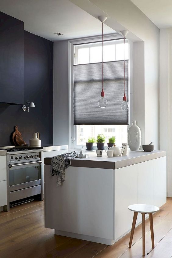 a chic monochromatic minimalist kitchen with concrete countertops and bulbs on red cords