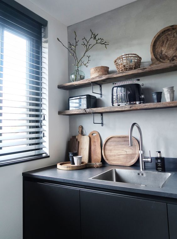 a contemporary black kitchen with sleek cabinets, concrete countertops and open wooden shelves