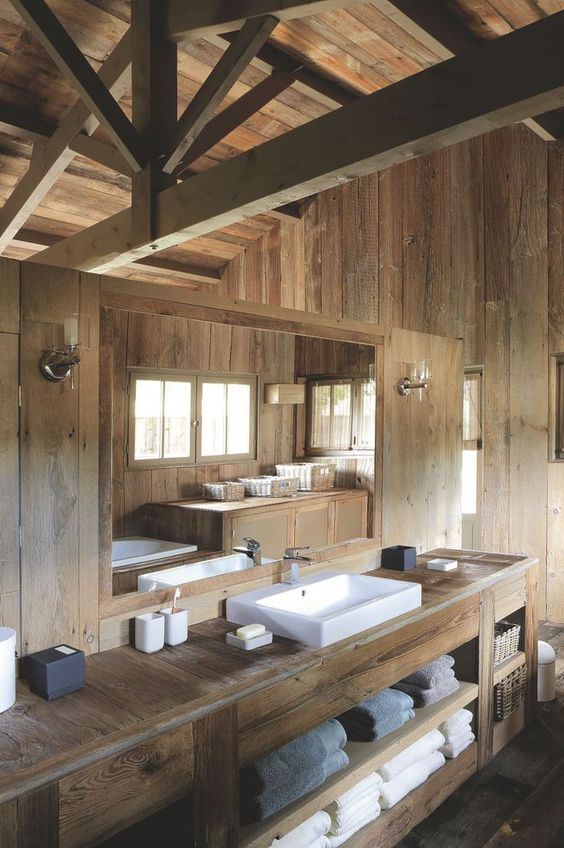 a contemporary chalet bathroom done with textural blonde wood, with wooden beams, a large vanity, a large sink and towels