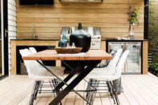 a contemporary dining area with a catchy zigzag leg table, white rattan chairs and a grill next to it