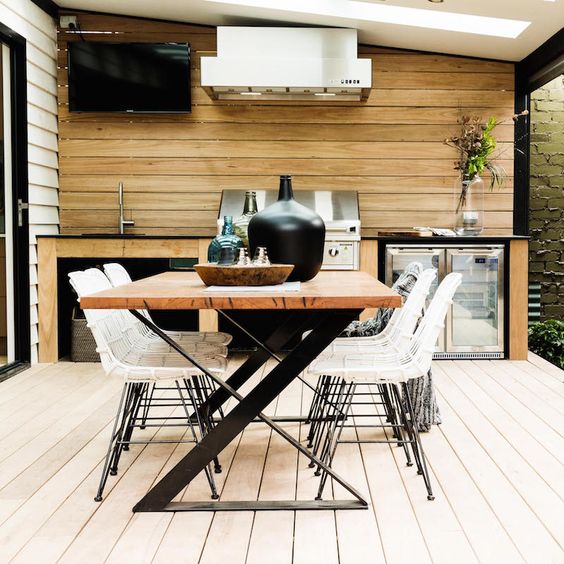 a contemporary dining area with a catchy zigzag leg table, white rattan chairs and a grill next to it