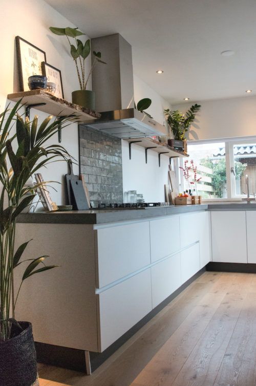 a contemporary kitchen with white cabinets, white walls, concrete countertops and a grey tile backsplash