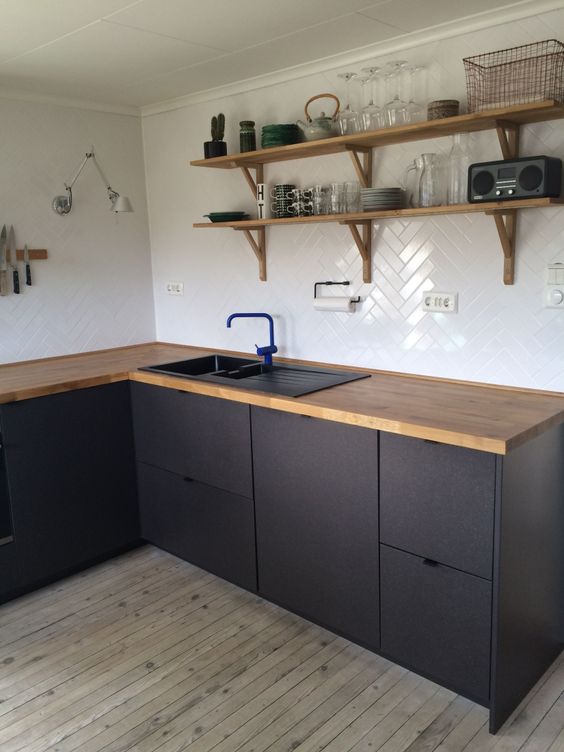 a contemporary matte black kitchen with light stained wooden countertops and matching wooden shelves looks chic