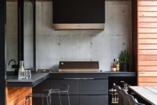a contemporary outdoor barbecue area done in black and stained wood, with matte cabinets, a grill, a hood and some meal spaces