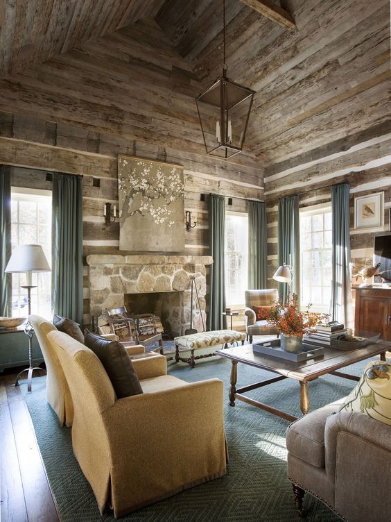 a cozy and elegant chalet living room with wooden walls and a ceiling, a stone fireplace, a wooden coffee table and neutral seating furniture