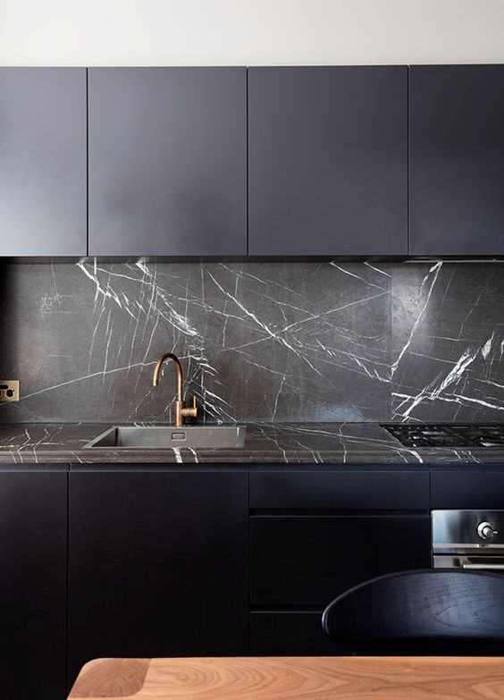 a dark stone countertop plus a matching backsplash make this midnight blue kitchen stunning