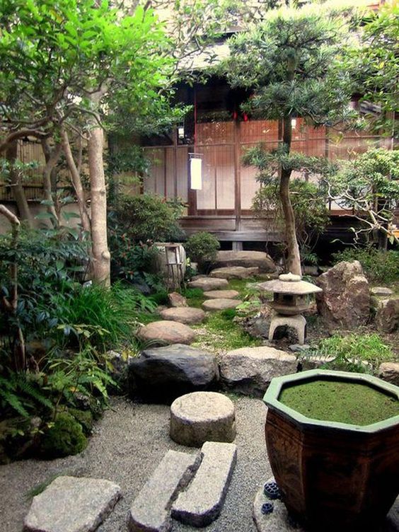 un fantástico patio trasero japonés con rocas, una linterna de piedra, vegetación y árboles y un cuenco con vegetación en el interior