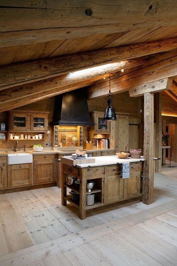 a light-colored chalet kitchen done with wooden beams, a skylight, stone countertops and vintage black lamps